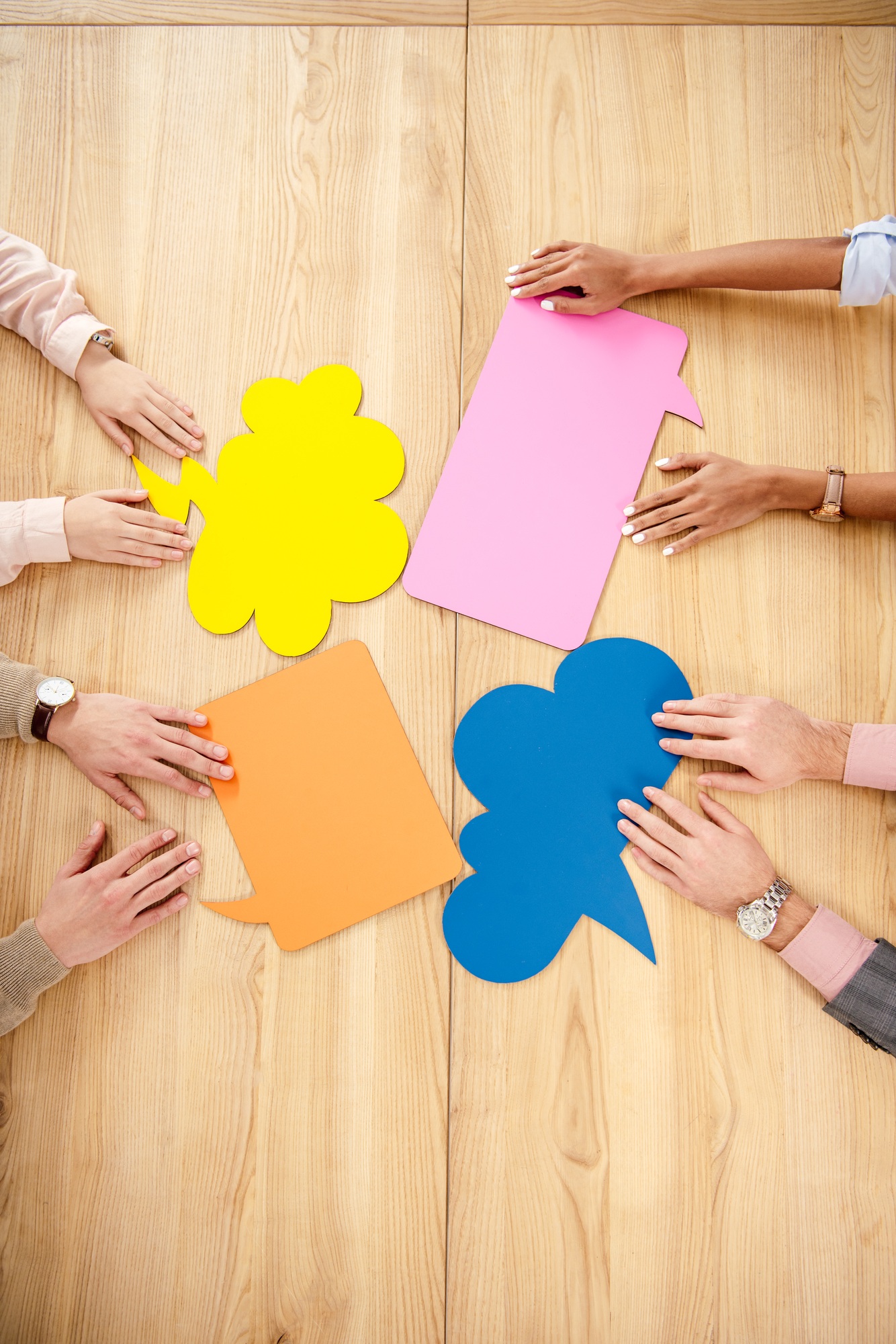 overhead view of multiracial business people at wooden table with empty colorful chat bubbles